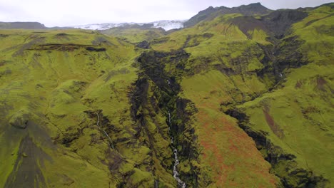 Secluded-green-volcanic-valley-with-glacier-in-background,-Iceland