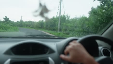 POV-shot-while-driving-a-car-on-an-empty-country-road-in-india-with-green-bushes-and-untouched-nature-at-the-side-of-the-road-during-a-calm-cloudy-morning-in-slow-motion