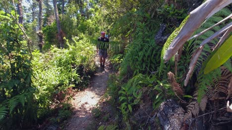 Slo-mo:-Male-hiker-jogs-down-green-jungle-path-toward-camera