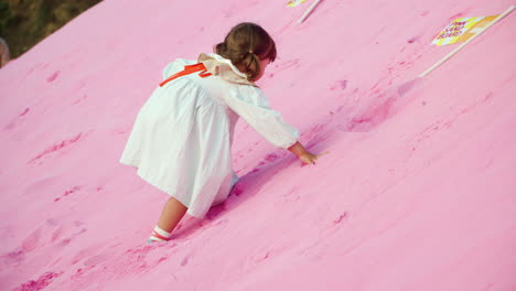 Little-Girl-Climbs-Up-on-Pink-Sand-Hill-at-Herb-Island-Park,-Pocheon,-Korea