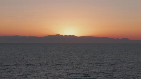 Aerial-view-passing-small-sailing-boat-travelling-Mediterranean-sea-rising-towards-glowing-Turkish-sunset-horizon