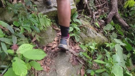 POV-close-up-follows-woman's-boots-as-she-hikes-up-stony-forest-path