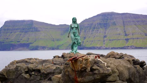Tilt-down-shot-of-the-Seal-Woman-Statue-in-the-coast-of-Mikladalur,-Faroe-Islands