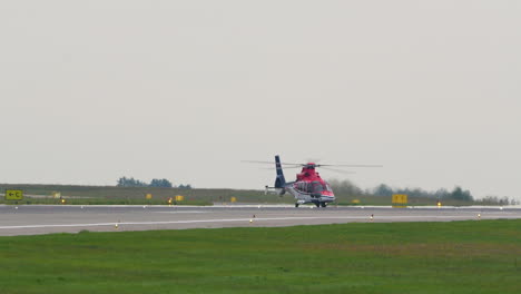 A-red-helicopter-on-an-airport-runway,-preparing-for-takeoff-or-landing