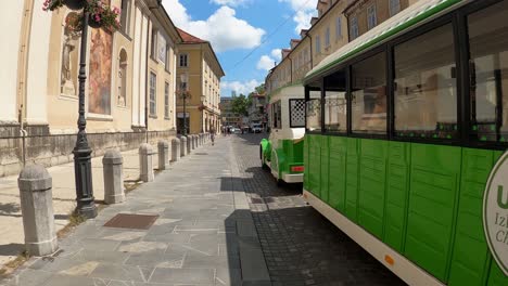 A-sightseeing-train-passes-outdoor-restaurants-in-Ljubljana,-Slovenia