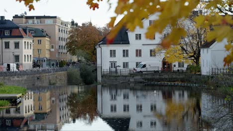 City-river-with-autumn-leaves-and-old-buildings-in-a-picturesque-urban-setting