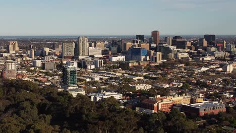 Drone-shot-of-the-Adelaide-CBD,-moving-left-to-right-and-getting-closer-to-the-city,-with-the-Adelaide-Parklands-in-the-foreground
