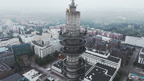 Aerial-shot-of-a-bleak-industrial-concrete-television-and-radio-link-tower-in-Pasila,-Helsinki,-Finland-on-a-bright-and-foggy-day