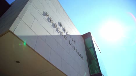 Exterior-De-La-Biblioteca-Pública-De-Whitby-Con-El-Nombre-Encima-De-La-Fachada,-Toma-Giratoria-Con-Luz-Solar-En-La-Arquitectura-Canadiense-Moderna