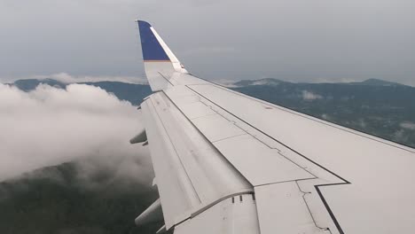 View-Looking-Along-Plane-Wing-Flying-Over-Clouds-With-Blue-Ridge-Mountains-In-Background