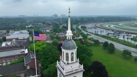 Aerial-orbit-around-Henry-Ford-Museum-and-American-flag-on-rainy-day-in-Dearborn,-Michigan
