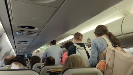 Impatient-Travellers-Standing-In-Aisle-Of-Plane-Waiting-To-Disembark-Flight