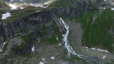 Majestic-waterfall-on-mountain-slide-with-fast-flowing-white-water,-aerial