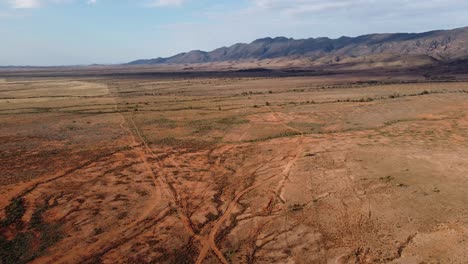 Drohnenaufnahme-über-Kargem,-Von-Dürre-Betroffenem-Land-Mit-Den-Spektakulären-Südaustralischen-Flinders-Ranges-Im-Hintergrund