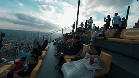 close-view-of-people-relaxing-and-talking-on-rooftop-terrace-with-overlooking-the-city-at-sunset-view