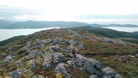 Person-With-Dog-Trekking-Over-Rugged-Terrain-Near-Rissa-And-Hasselvika-Towards-The-Mountain-Of-Blaheia,-Norway