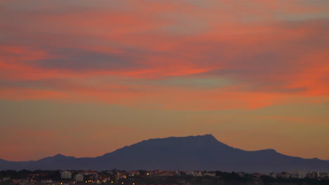 Filmischer-Eröffnungsdreh-Atemberaubend-Noch-Dramatisch-Leuchtend-Orangefarbene-Wolken-Sonnenuntergang-Abenddämmerung-Biarritz-Hossegor-Frankreich-Strand-Berg-Küstenlandschaft-Biarritz-Baskenland-Ruhiges-Wasser-Bucht