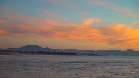Filmisch-Atemberaubend-Immer-Noch-Dramatisch-Leuchtend-Orange-Wolken-Sonnenuntergang-Abenddämmerung-Leuchtturm-Biarritz-Hossegor-Frankreich-Strand-Berg-Küstenlandschaft-Biarritz-Baskenland-Stadtlichter-Ruhiges-Wasser-Bucht