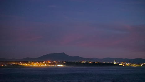 Cinematic-stunning-opening-shot-dramatic-evening-night-dusk-city-lights-lighthouse-Biarritz-Hossegor-France-beach-mountain-coastal-landscape-Biarritz-Basque-Country-calm-water-bay-scenic