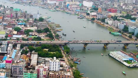 A-busy-bridge-over-the-Buriganga-River-in-Dhaka,-Bangladesh-with-ferries-in-the-water