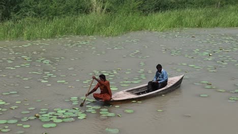 Close-up-aerial-shot-of-A-boatman-is-steering-a-wooden-boat-in-muddy-water