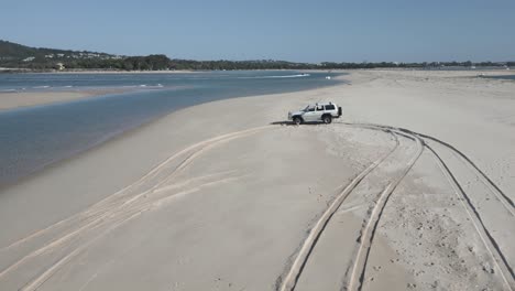 Low-aerial-orbits-truck-parked-on-Noosa-Heads-sand-beach-in-Australia