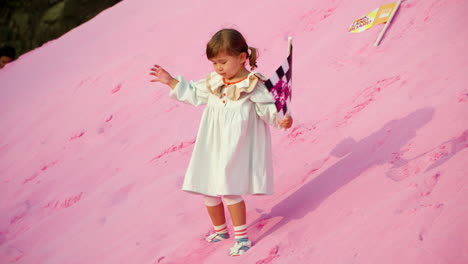 Playful-Child-With-Flag-Climbs-Pink-Sand-Hill-or-Mount-at-Sunset---Herb-Island-Park