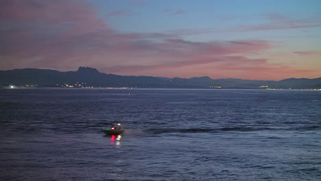 Filmisch-Atemberaubend-Noch-Nahaufnahme-Schnellboot-Biarritz-Hossegor-Frankreich-Rosa-Orange-Sonnenuntergang-Abenddämmerung-Strand-Berg-Küstenlandschaft-Biarritz-Baskenland-Stadt-Lichter-Ruhiges-Wasser-Bucht