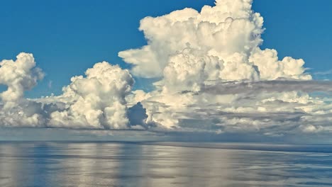 Ein-Atemberaubender-Zeitraffer-Riesiger-Weißer,-Flauschiger-Wolken,-Die-über-Einem-Ruhigen,-Spiegelnden-Ozean-Tanzen
