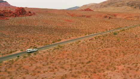 Aerial-tracking-shot-of-a-car-pulling-a-motorhome-trailer-through-deserts-of-USA