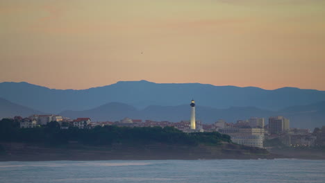 Cinematic-stunning-still-close-up-dramatic-bright-orange-clouds-sunset-dusk-lighthouse-bird-flying-Biarritz-Hossegor-France-beach-mountain-coastal-landscape-Biarritz-Basque-Country-calm-water-bay