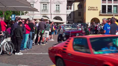Classic-cars-leaving-their-meetingpoint-Waltherplatz-Square-in-Bozen-–-Bolzano,-South-Tyrol-whilst-spectators-stand-on-both-sides-and-watch-the-cars-drive-off