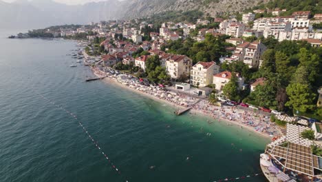 Aerial-drone-flying-above-busy-beach-in-Kotor,-Montenegro,-Travel-destination