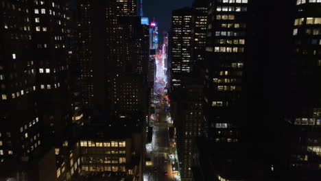 Drone-shot-tilting-over-the-7th-ave,-through-the-illuminated-midtown-to-Times-square,-NY