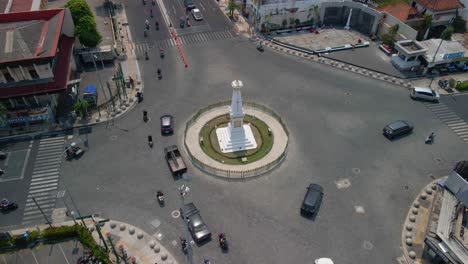 Aerial-orbiting-shot-of-Tugu-Yogyakarta-with-busy-traffic-on-road-in-city-during-sunny-day