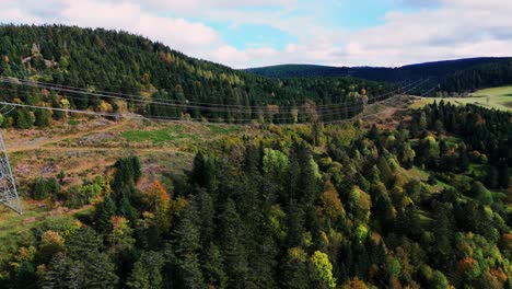Aerial-view-flying-along-tall-power-line-in-the-mountain-during-fall-season-in-4K
