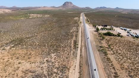 Disparo-De-Un-Dron-Siguiendo-A-Motocicletas-En-Una-Carretera-Del-Desierto