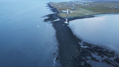 Drohne-Fliegt-Vom-Leuchtturm-An-Der-Isländischen-Küste-Weg-Und-Enthüllt-Einen-Wunderschönen,-Mit-Schwarzem-Sand-Bedeckten-Strand