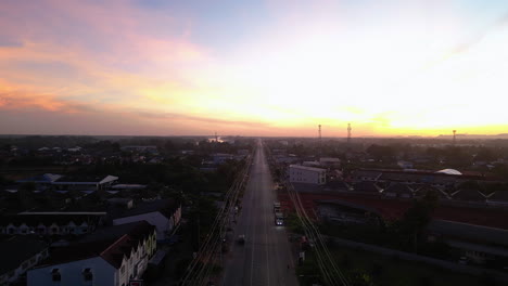 Aerial-flyover-main-road-in-Surat-thani-city-during-golden-sunset,-Thailand---Establishing-drone-shot