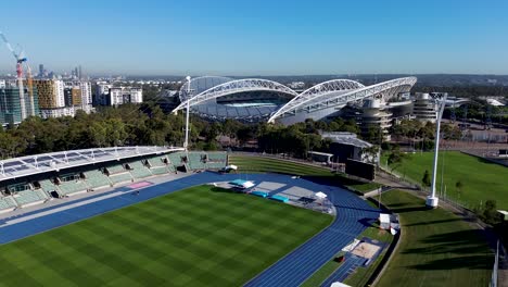 Dron-Aéreo-Instalaciones-De-Entrenamiento-De-Atletismo-Ovalado-Deportes-Fitness-Arena-Estadio-Accor-Pista-De-Atletismo-Asientos-Velódromo-Parque-Olímpico-De-Sydney-Bahía-De-Homebush-Nsw-Oeste-Sydney-Australia-Turismo-4k