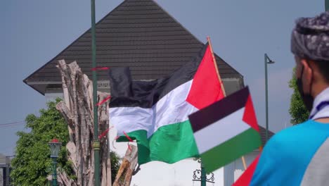 Slow-motion-shot-of-waving-Palestinian-flag-during-sunny-day-outdoors-at-demonstration-on-street-in-Asia---Yogyakarta,-Indonesia