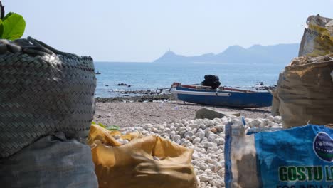 Scenic-landscape-view-of-beach,-local-fishing-boat-and-Cristo-Rei-statue-in-the-distance-in-Dili,-Timor-Leste,-Southeast-Asia
