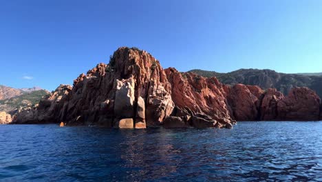 Primitive-landscape-of-Calanques-de-Piana-volcanic-eroded-rock-formations-in-Corsica-island-as-seen-from-moving-boat-in-summer-season,-France