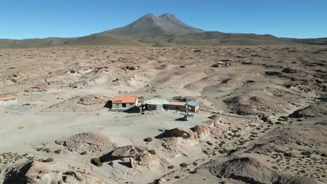 Aerial-view-of-lodge-in-the-deserted-landscape-of-Salar-de-Uyuni-and-at-the-foot-of-the-Thunupa-volcano,-Bolivia,-Mexico,-USA