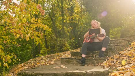 Young-musician-rehearses-song-Autumnal-woodland-park-golden-light