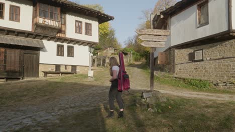 Female-musician-follows-signpost-direction-rural-charm-rustic-village