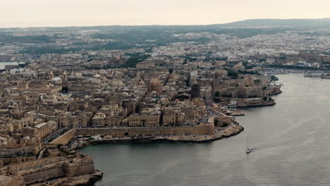 Drone-shot-circling-the-skyline-of-Valletta-city,-cloudy-evening-on-Malta-island