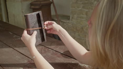 Young-woman-diarist-secures-personal-thoughts-in-leather-book-binder