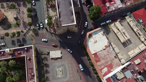 Overhead-shot-of-a-vehicular-intersection-with-moving-cars,-zooming-in-with-the-drone