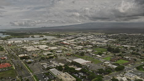 Kahului-Maui-Hawaii-Aerial-v9-drone-flyover-town-center-overlooking-at-townscape,-Kanaha-pond,-main-airport-and-island-landscape-with-stormy-clouds-in-the-sky---Shot-with-Mavic-3-Cine---December-2022